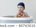 A small child rushes his teeth while sitting in the bathroom 80743616