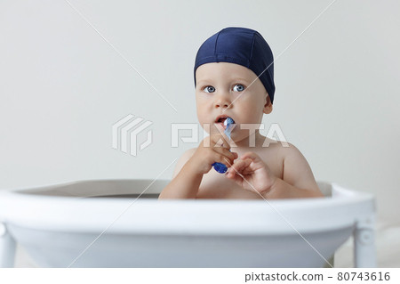 A small child rushes his teeth while sitting in the bathroom 80743616