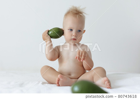 little boy holds avocado in his hands and smiles. 80743618