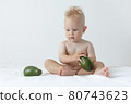 little boy holds avocado in his hands and smiles 80743623