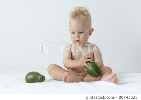 little boy holds avocado in his hands and smiles 80743623