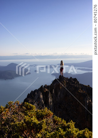 Adventurous Caucasian Woman Hiking on top of a Rocky Mountain Cliff 80745276