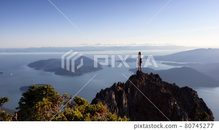Adventurous Caucasian Woman Hiking on top of a Rocky Mountain Cliff 80745277