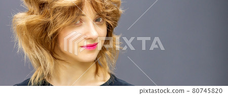 Beautiful young caucasian woman with a red short curly hairstyle on dark background. Beautiful young caucasian woman with a red short curly hairstyle on dark background. 80745820
