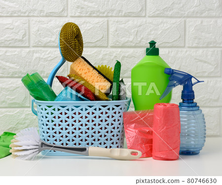 plastic basket with brushes, disinfectant in a bottle, rubber gloves on the background of a white brick wall 80746630