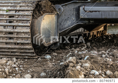 Heavy excavator (digger machine) track detail, some stones in foreground. Abstract industrial / construction background. Heavy excavator (digger machine) track detail, some stones in foreground. Abstract industrial / construction background. 80746971