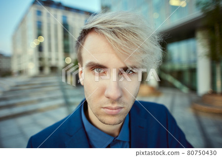 Angry face of young businessman in front of an office building in evening. 80750430