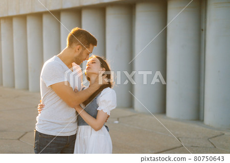 Medium shot portrait of happy romantic young couple in love hugging while man touching neck of girlfriends with hand Medium shot portrait of happy romantic young couple in love hugging while man touching neck of girlfriends with hand 80750643