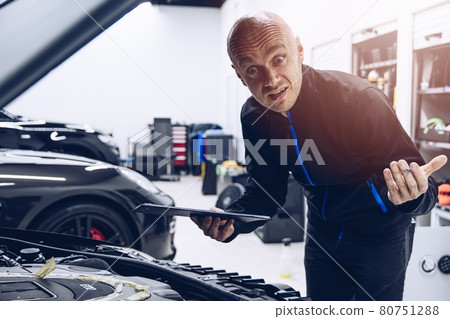Confused car service mechanic checking engine Confused car service mechanic checking engine 80751288