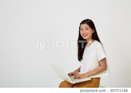 woman with laptop computer sitting cross legged and looking woman with laptop computer sitting cross legged and looking 80751386