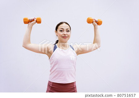 Woman in sportswear is engaged with dumbbells 80751657