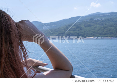 a young woman looks at the shore from a ship a young woman looks at the shore from a ship 80753208