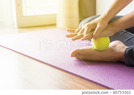 Woman massage with tennis ball to her foot in bedroom,Feet soles massage for plantar fasciitis Woman massage with tennis ball to her foot in bedroom,Feet soles massage for plantar fasciitis 80753302