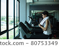 Side view of beautiful girl running on treadmill at gym 80753349