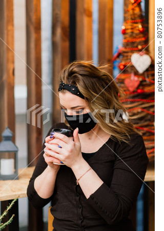Precautions in the public places after quarantine ended. Young woman with medical mask in cafe Precautions in the public places after quarantine ended. Young woman with medical mask in cafe 80753896