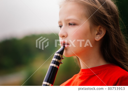 Young attractive girl playing clarinet, ebony in fall park Young attractive girl playing clarinet, ebony in fall park 80753913