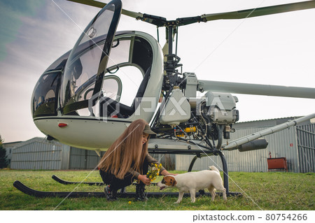 Carefree preteen girl playing with dog near helicopter Carefree preteen girl playing with dog near helicopter 80754266