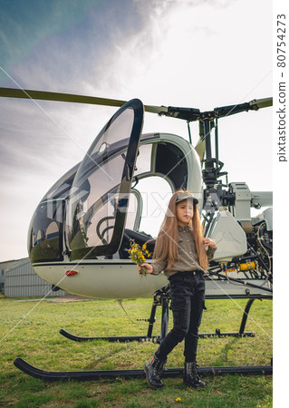 Preteen girl with bouquet of wildflowers standing near helicopter Preteen girl with bouquet of wildflowers standing near helicopter 80754273