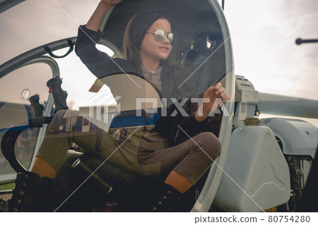 View through glass of helicopter cockpit of smiling preteen girl on pilots seat View through glass of helicopter cockpit of smiling preteen girl on pilots seat 80754280