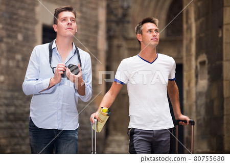 Travelers standing with baggage at street and taking photos Travelers standing with baggage at street and taking photos 80755680