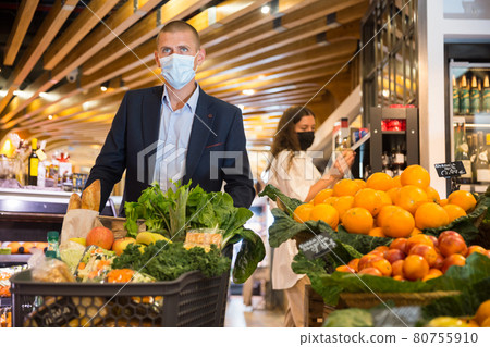 Portrait of a young male in a protective mask with a grocery cart in the supermarket 80755910