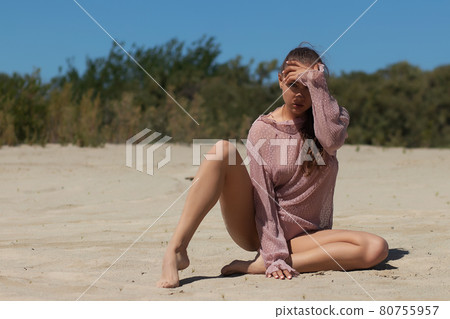 Fashionable woman in stylish beachwear sitting on sand 80755957