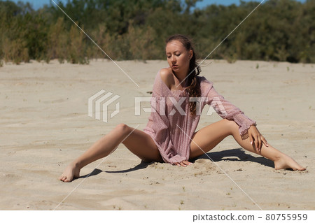 Relaxed woman in stylish beachwear sitting on sand 80755959