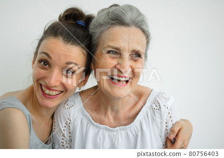 Happy senior mother is hugging her adult daughter, the women are laughing together, sincere family of different age generations having fun on white background, mothers day. Happy senior mother is hugging her adult daughter, the women are laughing together, sincere family of different age generations having fun on white background, mothers day. 80756403