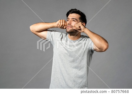 Sleepy young handsome Caucasian man rubbing eyes after wake up and looking away Sleepy young handsome Caucasian man rubbing eyes after wake up and looking away 80757668