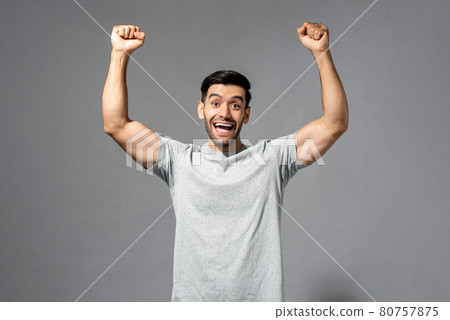 Young happy healthy Caucasian man smiling and raising his fists Young happy healthy Caucasian man smiling and raising his fists 80757875