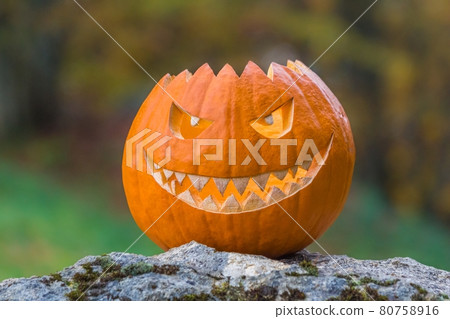 Scary smiling face halloween pumpkin on a stone Scary smiling face halloween pumpkin on a stone 80758916