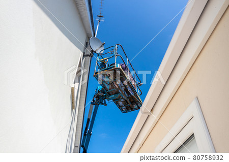 Worker on a aerial access platform, cherry picker, cleaning house 80758932
