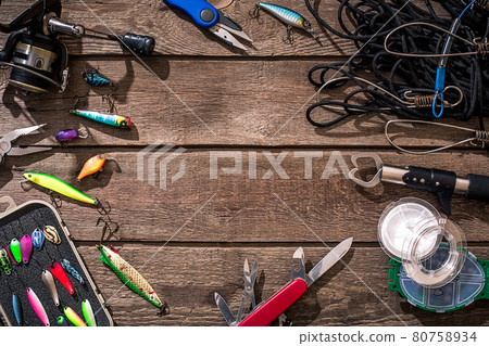 Fishing tackle - fishing spinning, fishing line, hooks and lures on wooden background. 80758934