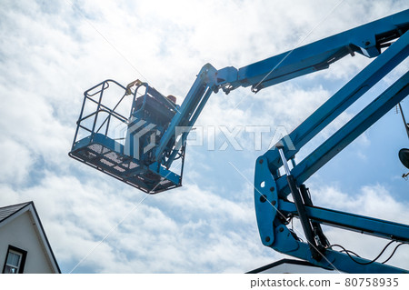 Worker on a aerial access platform, cherry picker, cleaning house 80758935