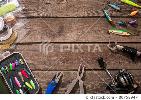 Fishing tackle - fishing spinning, fishing line, hooks and lures on wooden background. 80758947