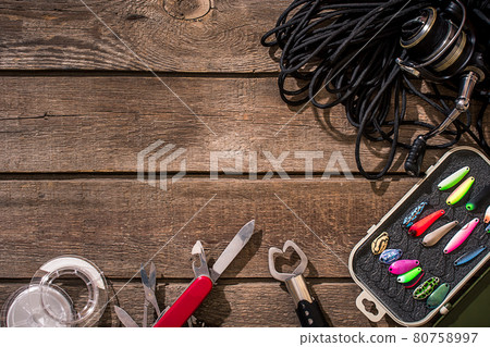 Fishing tackle - fishing spinning, fishing line, hooks and lures on wooden background. 80758997