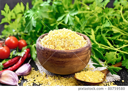 Bulgur in bowl with vegetables on black board Bulgur in bowl with vegetables on black board 80759580