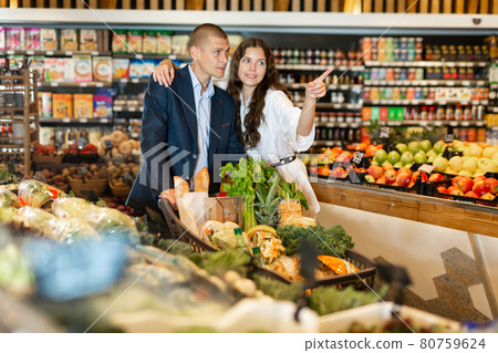Portrait of a happy young couple in a supermarket with a full grocery cart 80759624