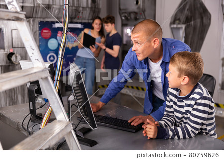 Portrait of a father and son in front of a computer in the quest room 80759626