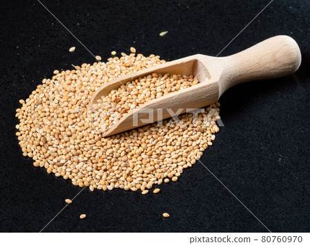 scoop on pile of yellow proso millet seed on black 80760970
