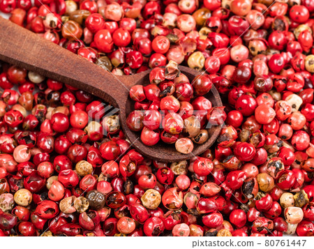 spoon on pile of pink peppercorns closeup 80761447