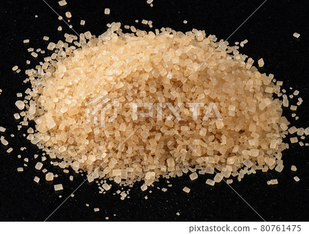 handful of demerara brown sugar closeup on black 80761475