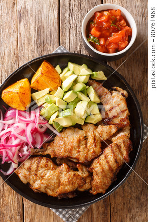 Poc chuc is a Mexican dish of meat pork, that is prepared in citrus marinade and cooked over a grill served with pickled onion and avocado closeup on the table. Vertical top view Poc chuc is a Mexican dish of meat pork, that is prepared in citrus marinade and cooked over a grill served with pickled onion and avocado closeup on the table. Vertical top view 80761968