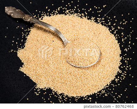 spoon in pile of amaranth grain on black plate spoon in pile of amaranth grain on black plate 80762468