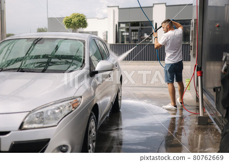 Young man cleaning his car with a jet sprayer. Self-service car washing 80762669