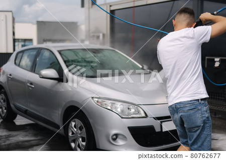 Back view of young man cleaning his car with a jet sprayer. Self-service car washing 80762677