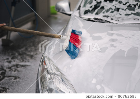 Close up of female washing the car with shampoo and brushes. Self car washing outdoor. Lather runs down the back of the car Close up of female washing the car with shampoo and brushes. Self car washing outdoor. Lather runs down the back of the car 80762685