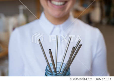 A woman holds a jar of reusable steel tubes. Eco concept A woman holds a jar of reusable steel tubes. Eco concept 80763023