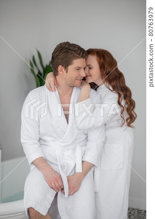 A couple in white bathrobes hugging and feeling in love A couple in white bathrobes hugging and feeling in love 80763979
