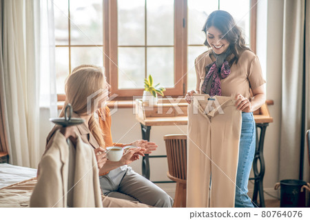 Dark-haired woman showing her new buyings to her friends 80764076